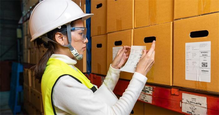 Warehouse worker checking supplier packaging for visible damage before inspection